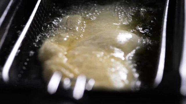 Golden panzerotto deep-frying in bubbling oil, close-up view, showing crispy texture and rich, savory Italian street food appeal.