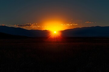 A stunning sunrise over the mountain peaks, casting golden rays across the open landscape, with rich colors blending into the twilight sky.
