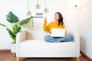 2025 resolutions with young woman pointing resolutions cheerful and happy new year with laptop on the sofa in living room.  Star together new year 2025