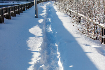 A snow covered path with a fence on the side