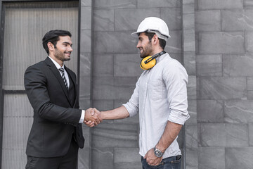 Project engineer and young businessman make high five for success business deal at outdoor office building project.