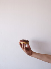 A hand holding a chocolate glazed doughnut