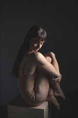 Naklejka premium Thoughtful Dancer Sitting Gracefully in Soft Studio Light