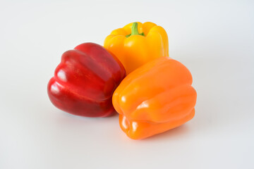 three red, orange and yellow peppers are laying next to each other