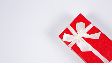 A red gift box wrapped by ribbon with tied bow isolated on white background. Presents and gift boxes for festivals and celebrations.