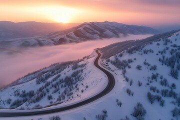 Winding mountain road through snowy landscape at sunrise