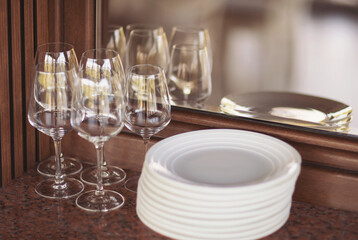 Prepared clean dishes for dinner for outdoor party on a window. Stacked clean dishes and glasses. 