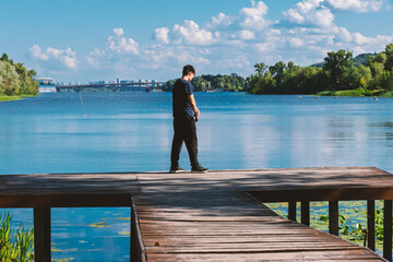 A teenager walks along a wooden pier against the backdrop of a river in Kyiv.