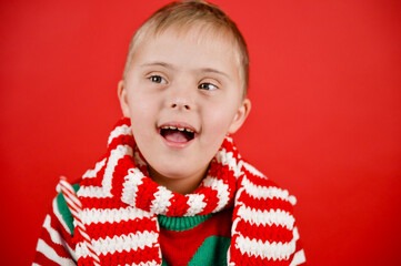 Happy child with Down syndrome in Christmas scarf having fun and laughing in studio. Christmas...