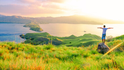 Young traveler man standing on the top of mountain at Gili Lawa, Komodo National Park, Indonesia. summer background and summer holiday concept.  © Balnyes Visuals