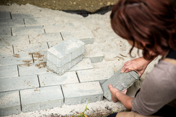 a woman lays paving stones in her garden