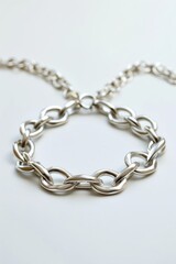 Obraz premium Silver chain bracelet lying on white background, intricate design with delicate links