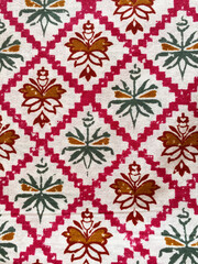 pink cotton fabric featuring green and maroon geometric floral outline buttas, block-printed with precision.