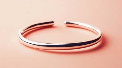 Naklejka premium Simple silver cuff bracelet, isolated on pastel peach background, ideal for minimalist style