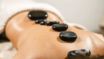 Woman receiving hot stone massage therapy on back in spa