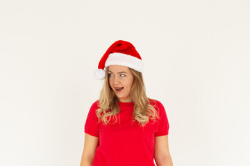 Surprised young Santa woman in Christmas hat keeping smile looking aside isolated on white background, studio portrait. Happy New Year celebration merry holiday concept