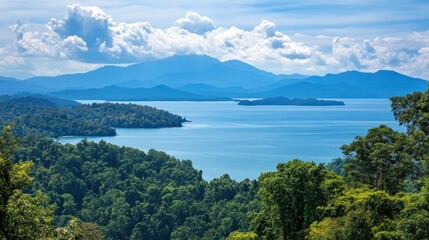 Serene landscape featuring mountains, a lake, and lush greenery under a blue sky.