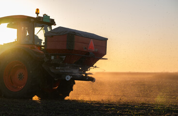 Fototapeta premium Farmer fertilizing arable land with nitrogen fertilizer