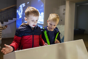 Children read about the mammoth in the natural history museum. In the foreground is the skeleton of...