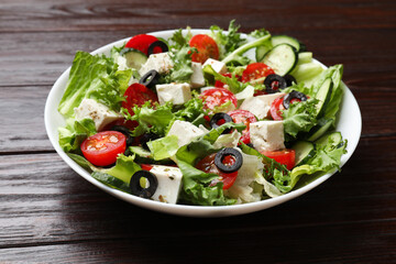 Delicious salad with feta cheese on wooden table, closeup