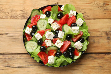 Delicious salad with feta cheese on wooden table, top view