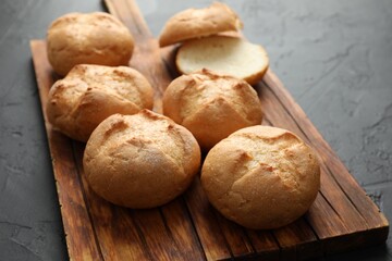 Board with homemade tasty buns on black textured table, closeup