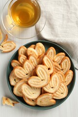 Delicious palmier cookies with tea on white wooden table, top view