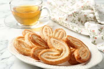 Delicious palmier cookies with tea on white marble table, closeup