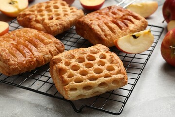 Delicious puff pastries with fruit filling and apples on grey table, closeup