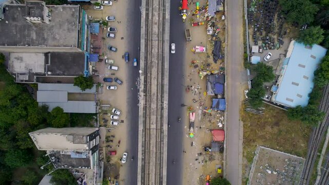 aerial drone shot straight down showing metro train tracks and huge colorful Ravan Raavan effigies being sold on the side of the street for the hindu festival of Dussehra