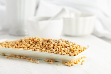 Pine nuts in white dish on a white background.
