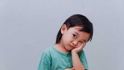 Portrait Asian boy kid making sleep gesture on grey isolated studio background.