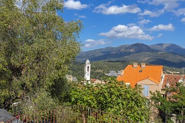 Obraz premium Charming street scene in Corte's historic old town, Corsica, with shops, church, and cobblestone paths