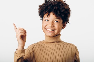 Joyful african american girl pointing and smiling enthusiastically at an imaginary object against a...