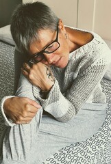 Front view of a young depressed and sad woman sitting on the bed. Vertical image. Concepts of...