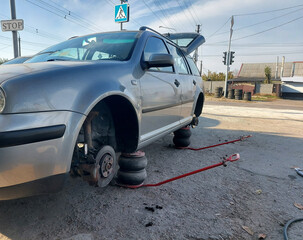 replacing car wheels at a tire shop. The car without wheels is raised on jack stands. car service