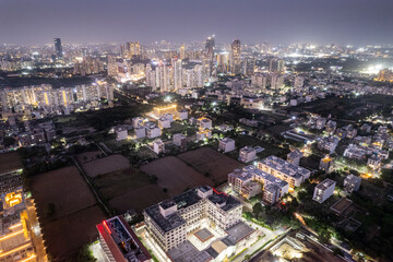 Fototapeta premium Aerial drone shot of Delhi cityscape with small shopping centers, malls, offices, houses to skyscrapers in the distance with well lit streets with traffic