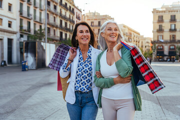 Beautiful senior women bonding outdoors in the city - Attractive cheerful mature female friends having fun, shopping and bonding, concepts about elderly lifestyle