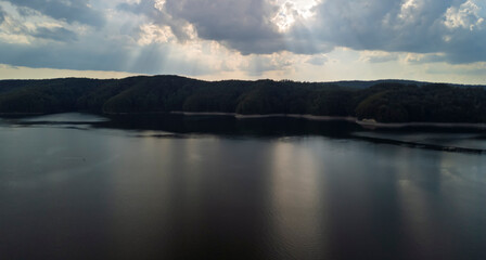 Serene landscape of a tranquil lake surrounded by lush green hills and dramatic skies, perfect for nature lovers and relaxation