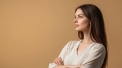 Fototapeta premium A woman with long hair is standing in front of a tan wall