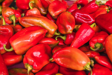 A vibrant and fresh display of red peppers at a market. The glossy texture and rich color of these...