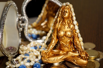 A female Buddha statuette with jewelry and coins.
