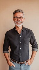 Fototapeta premium Smiling stylish middle aged business man, happy older mature businessman professional executive wearing gray shirt looking at camera standing isolated on beige background. Portrait. Copy space.