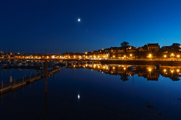 Fototapeta premium Port de Camaret à l'heure bleue, les reflets des voiliers illuminent la mer calme d’Iroise en automne.