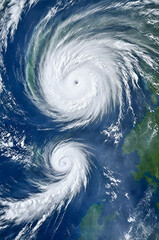 Satellite view of two hurricanes above the earth.