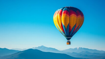 Obraz premium A colorful hot air balloon soars over majestic mountain ranges, touching the boundless blue sky.