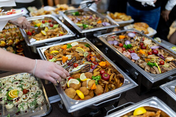 A vibrant buffet spread featuring an array of colorful dishes at a lively event with guests serving themselves