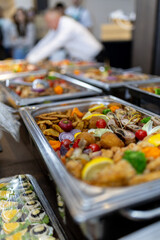 Colorful buffet spread featuring a variety of dishes with vegetables and seafood at a catered event in a modern setting