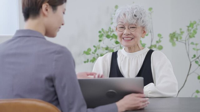 パソコンで説明する営業マンとシニア女性（ビジネス・保険）
