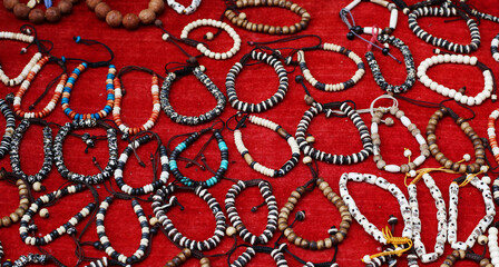 A vibrant collection of traditional beaded bracelets displayed on a red cloth, showcasing intricate patterns, natural colors, and diverse designs that reflect Nepalese artistry and craftsmanship.